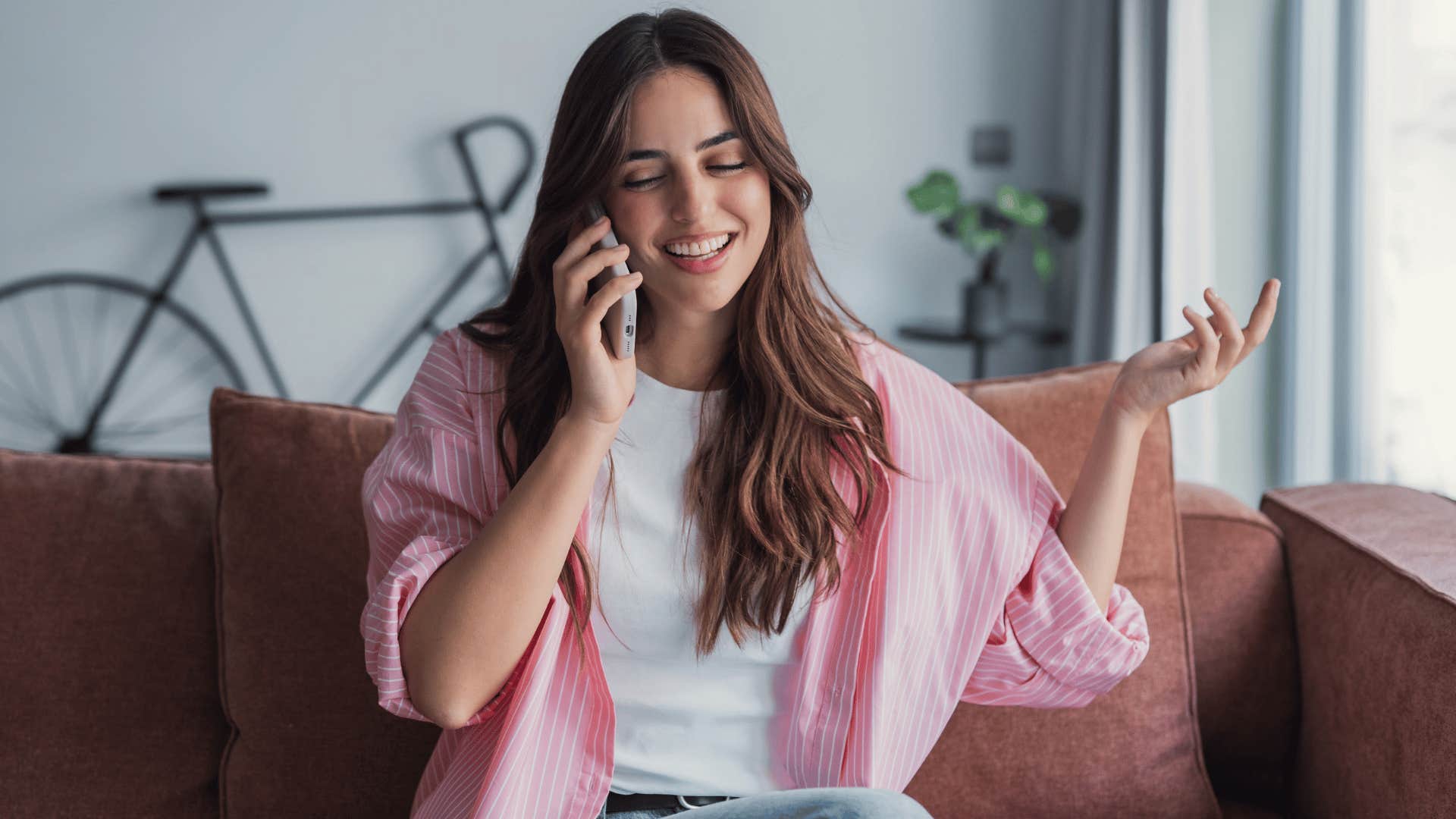 woman with white shirt on the phone smiling as she says i know i'm a catch