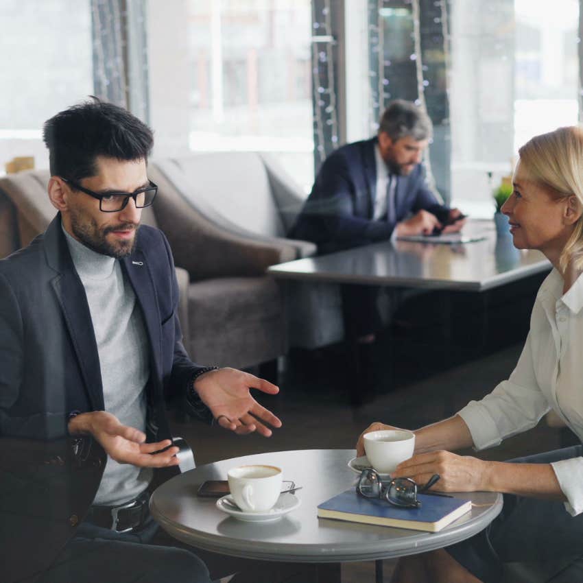 Overwhelmed employee talking to a coworker about her heavy workload while working at the office