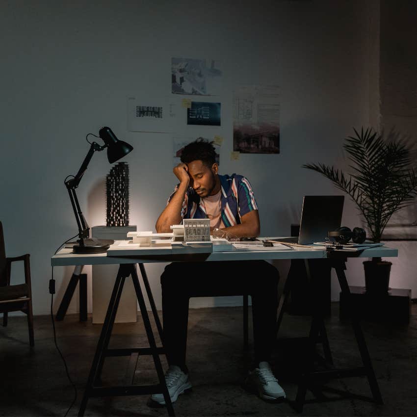 Employee working late at an office while appearing exhausted and surrounded by unfinished tasks