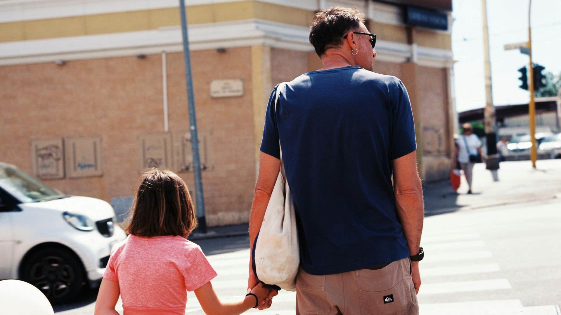 father aware of his surroundings crossing street with his daughter
