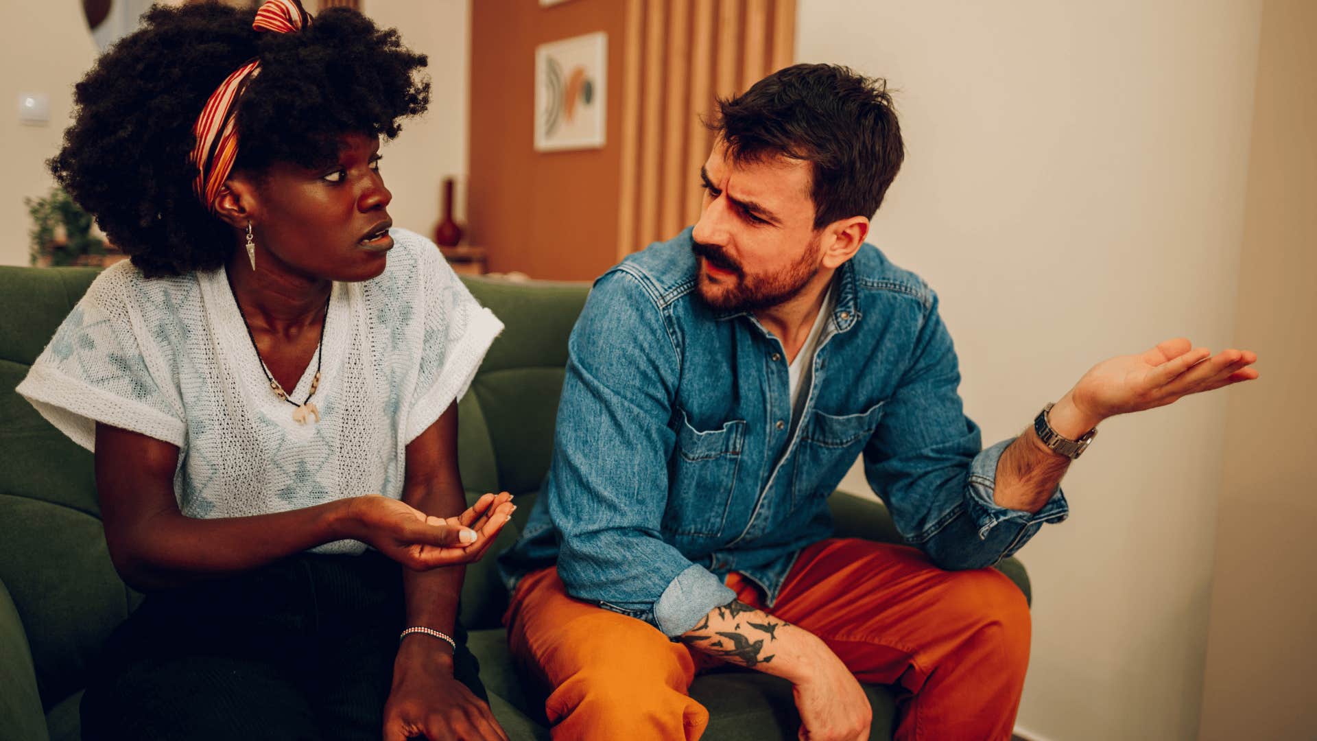 couple arguing on couch as man in orange pants says at least i admitted it