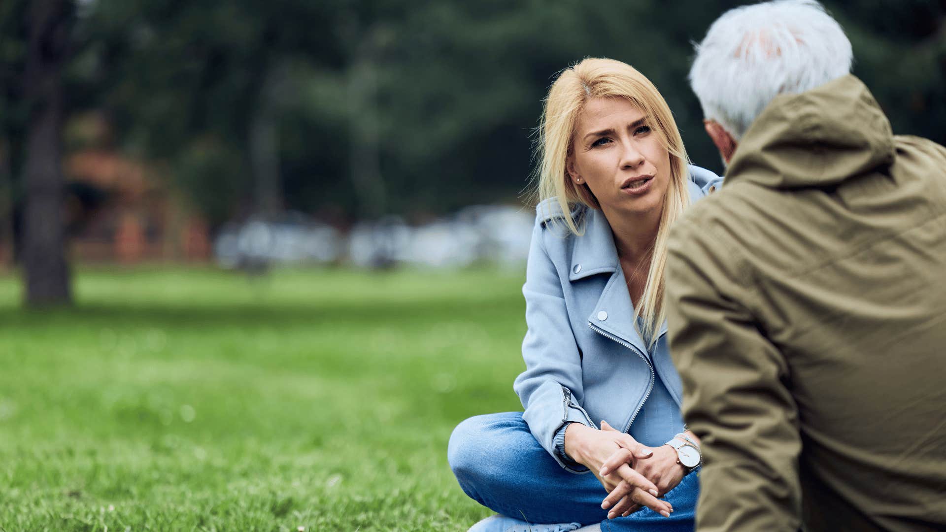 woman in blue shirt telling man i'm just trying to protect myself as they sit on grass