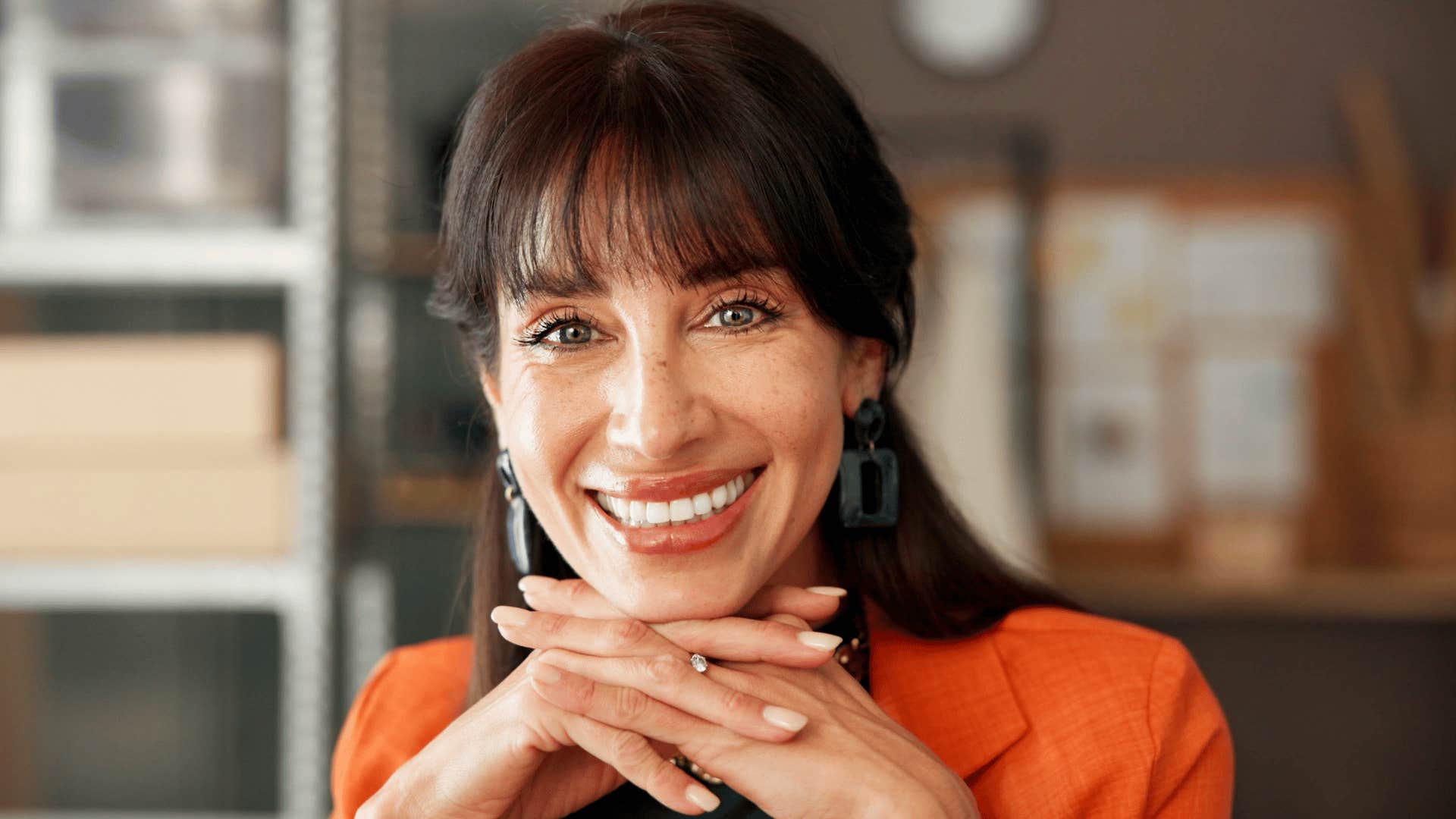 woman in orange shirt smiling at the camera as she thinks you know i have a good heart