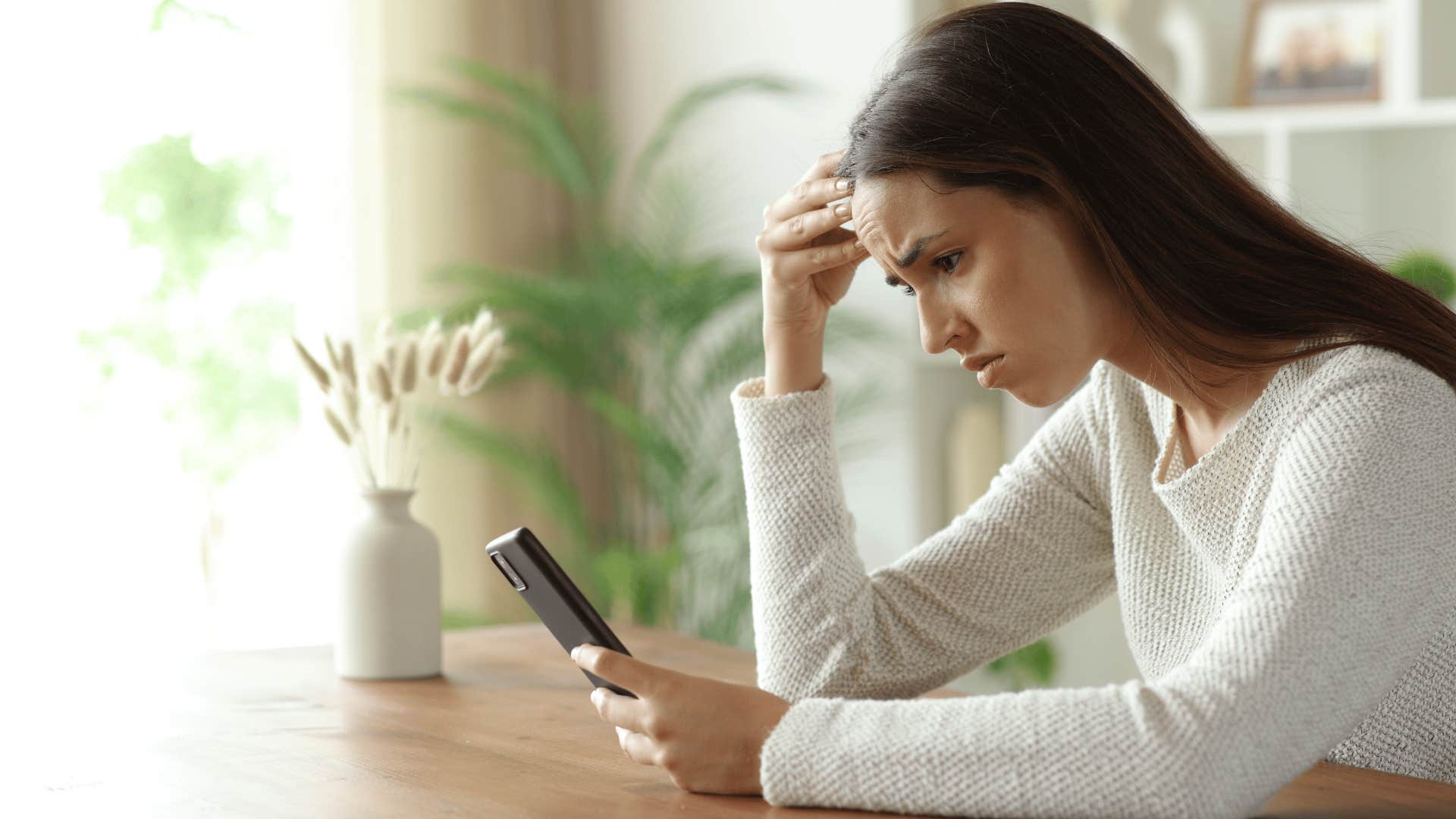woman with white shirt staring at phone as she thinks about how she had some unexpected expenses come up