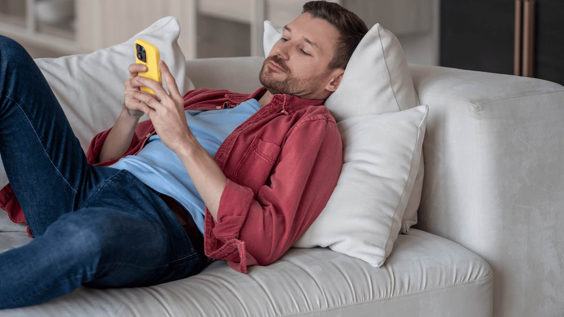 man in blue shirt on the phone saying i don't feel like trying today as he lays on the couch 
