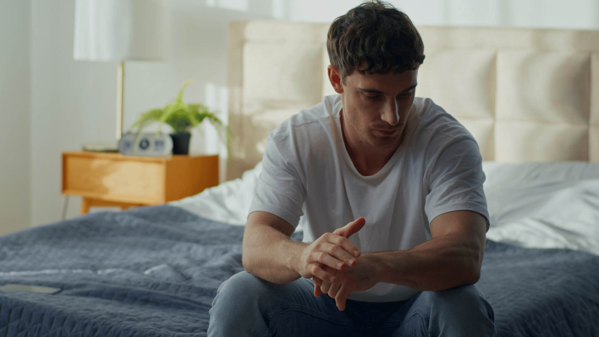 man in white shirt on the bed thinking i miss how things used to be