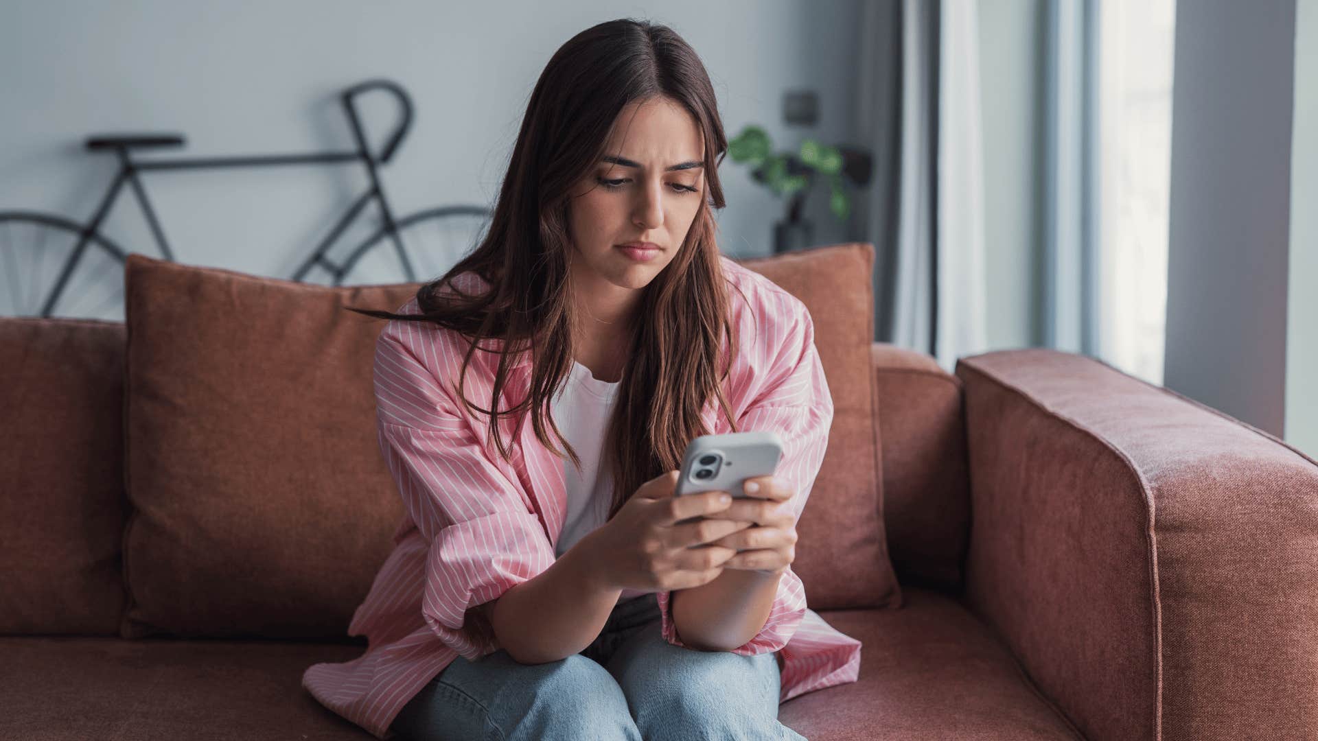 woman in pink jacket looking at the phone as she texts i've been leaving everyone on read lately