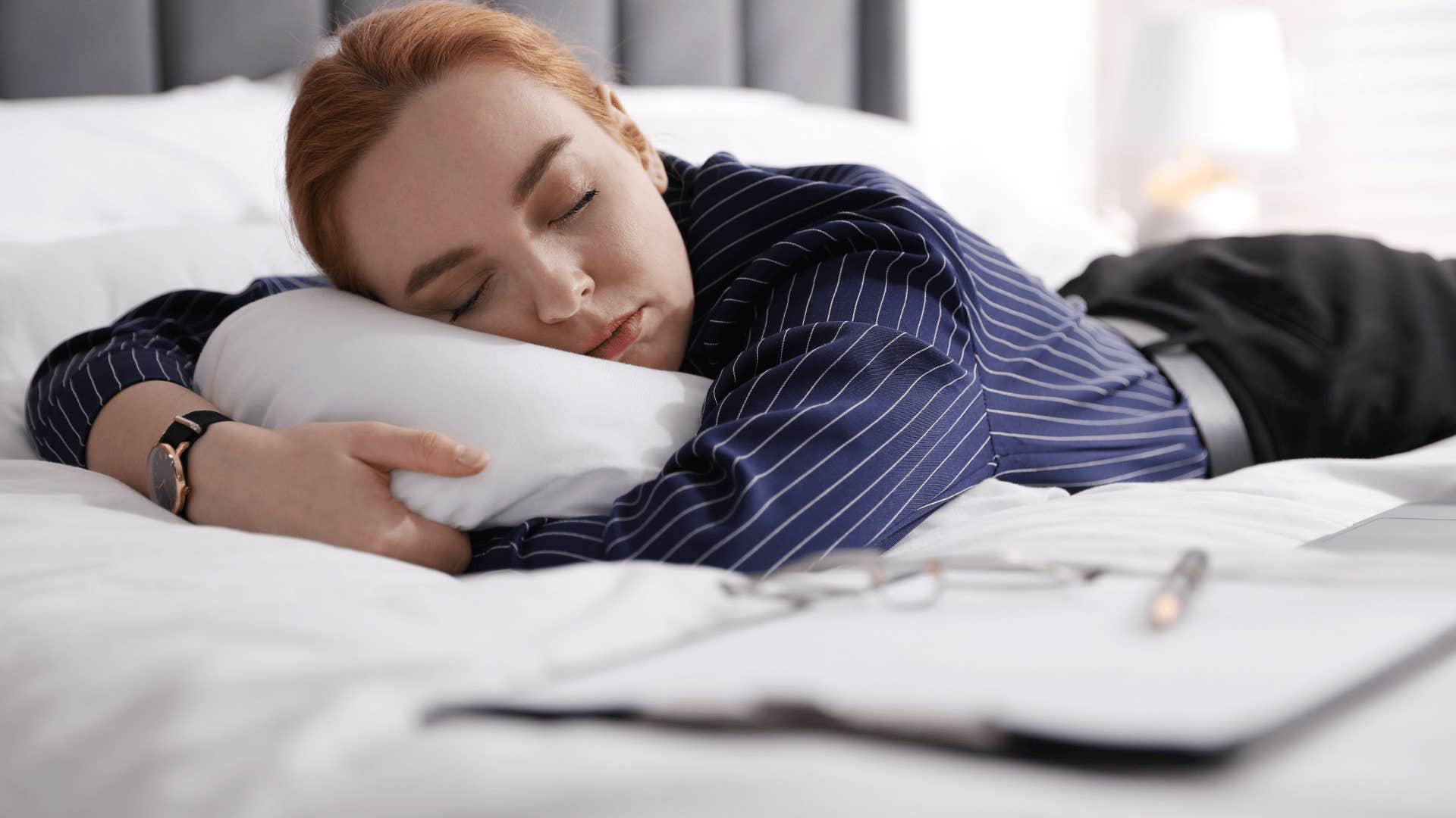 woman in navy blue shirt laying on the bed as she thinks i've been sleeping so much lately