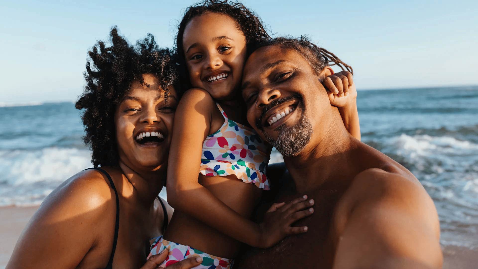 family smiling on the beach while on vacation