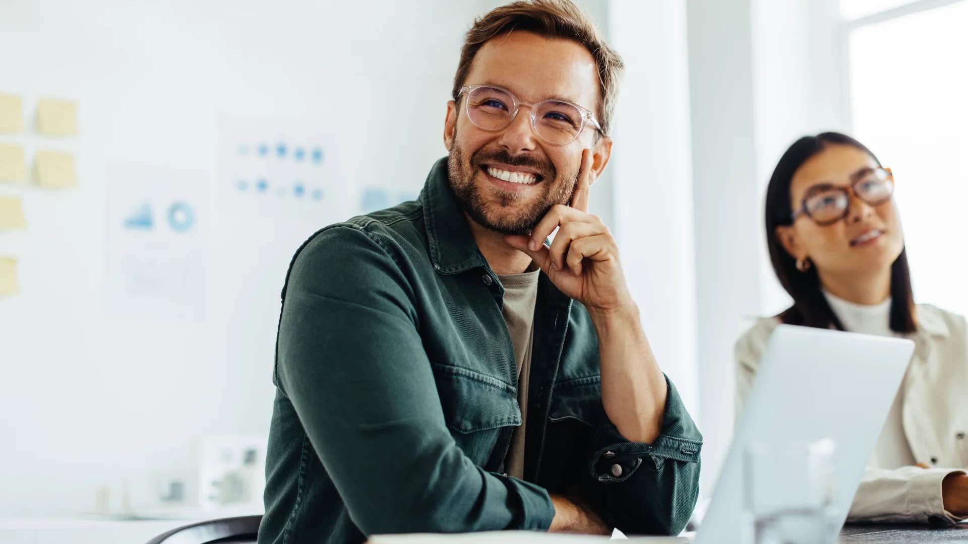 smiling man listening intently to colleague at work