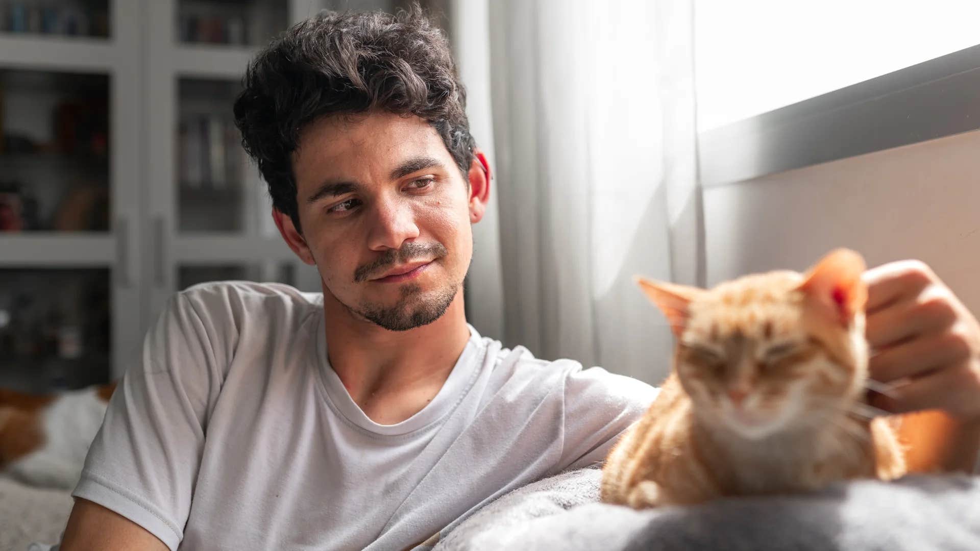 open-minded man petting his cat at home