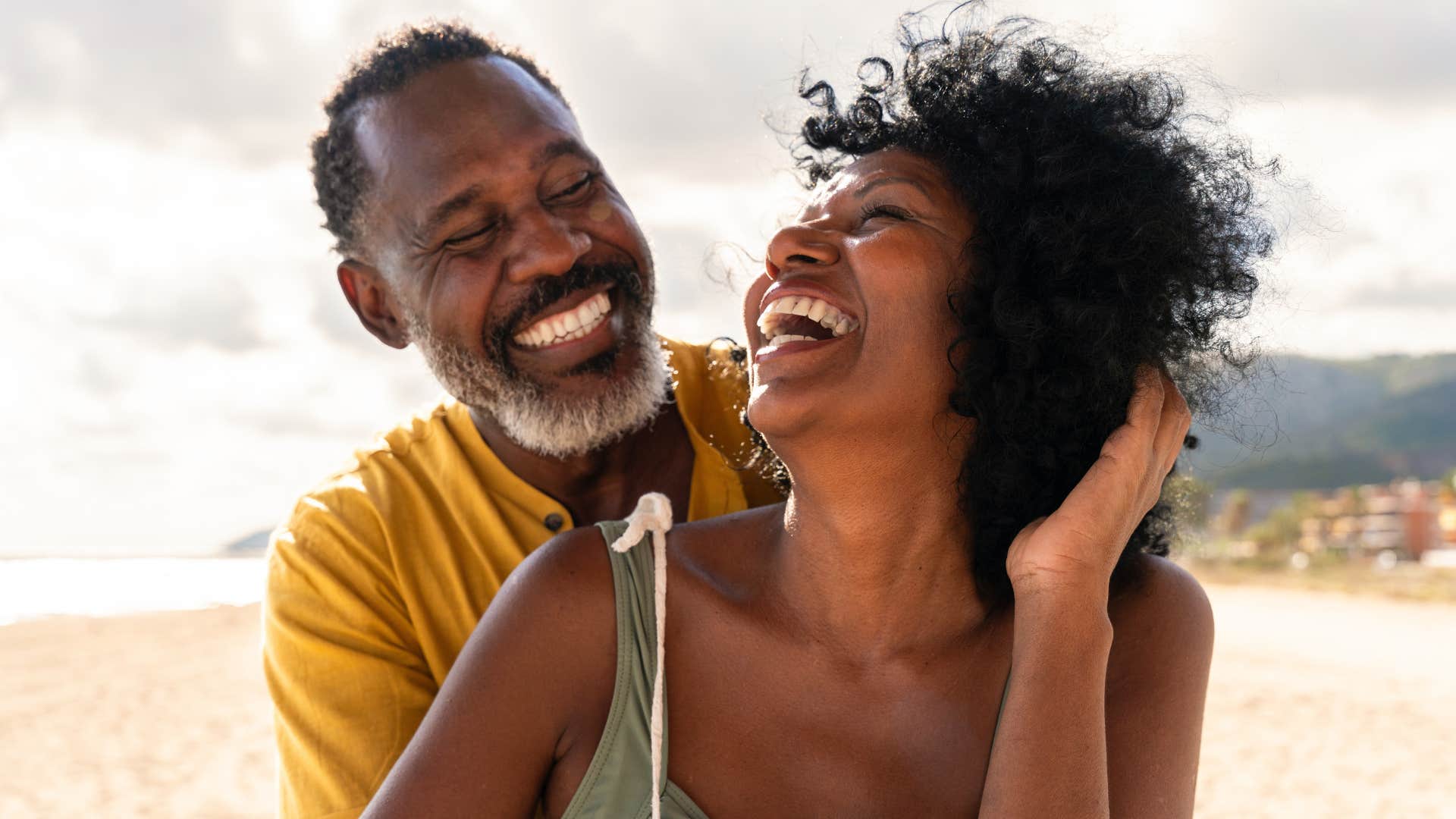 happily married man smiling and laughing with wife on vacation because she makes him happy