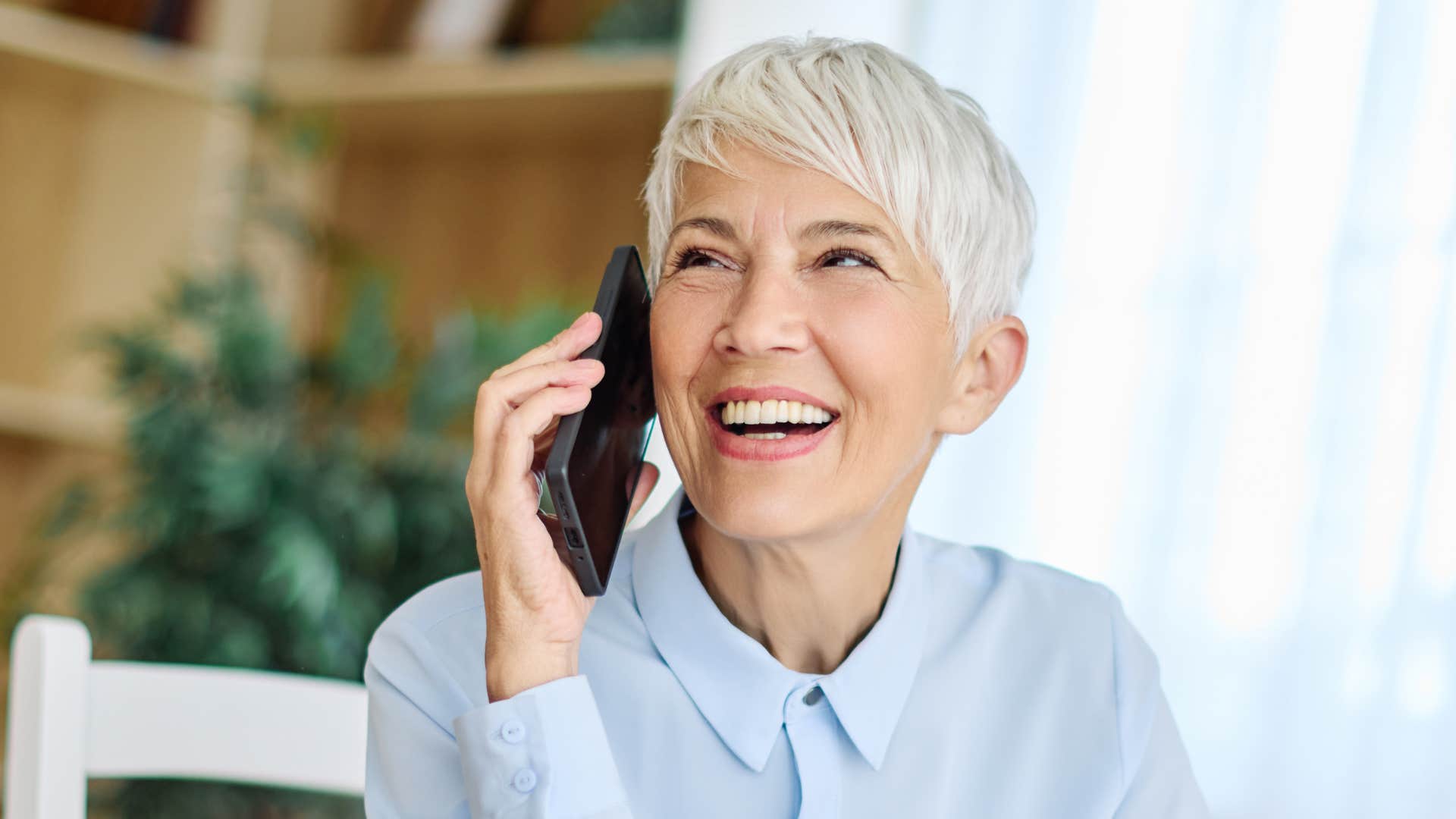 woman who hates small talk smiling talking on phone telling friend I need to let you go to politely end conversation