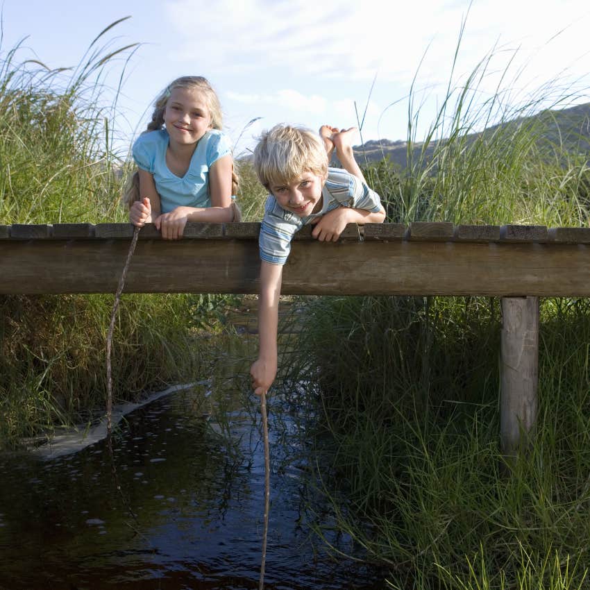brother and sister playing in river with sticks building resilience