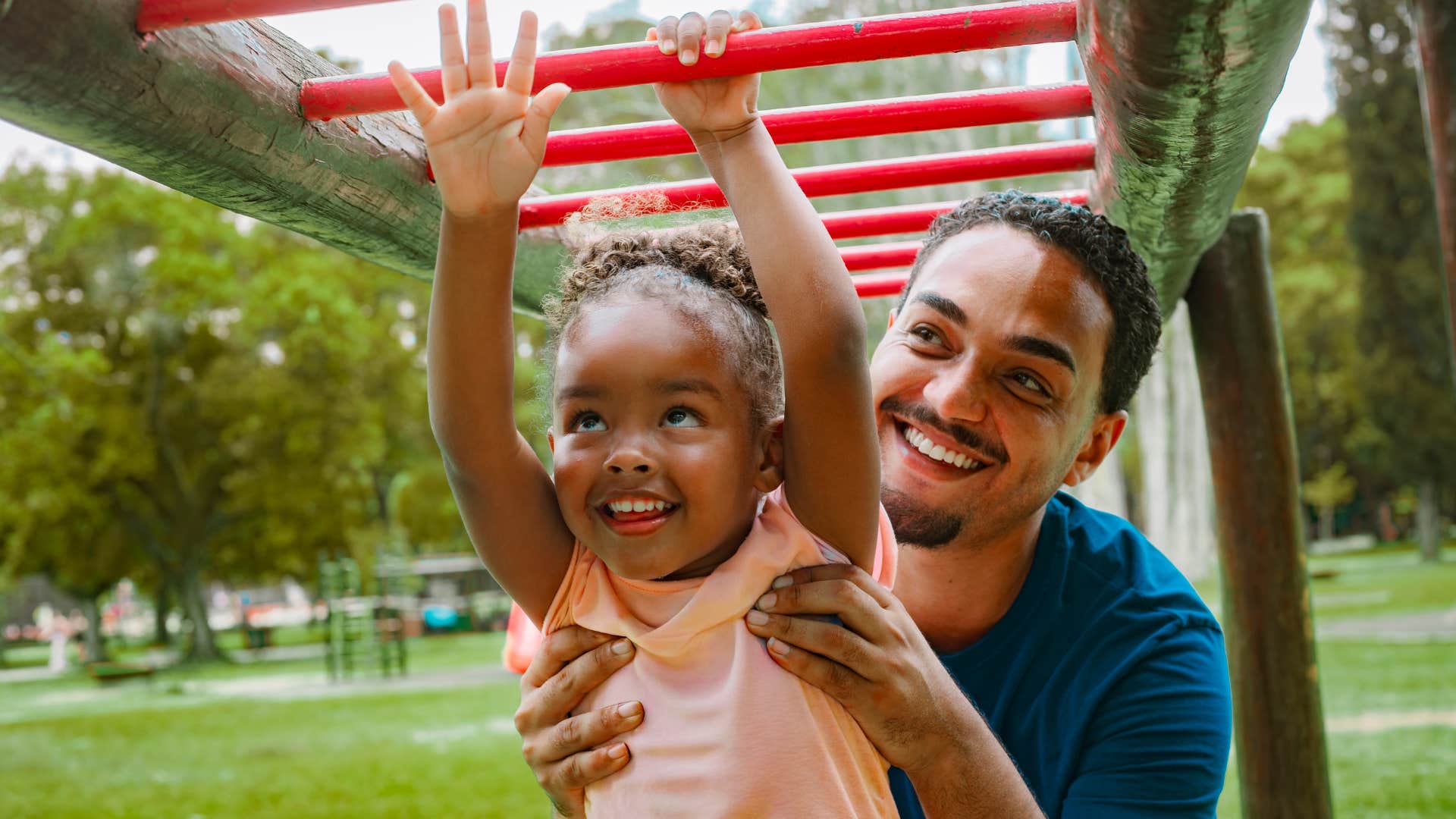 tough dad helping daughter on monkey bars teaching her to never give up
