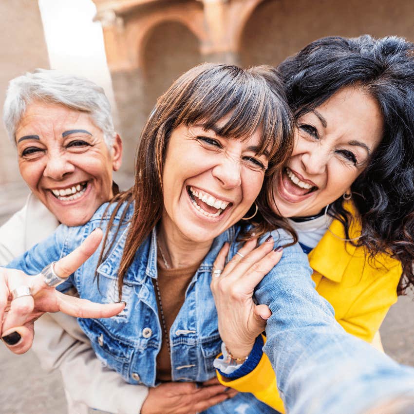 smiling gen-x friends hugging each other close for a selfie