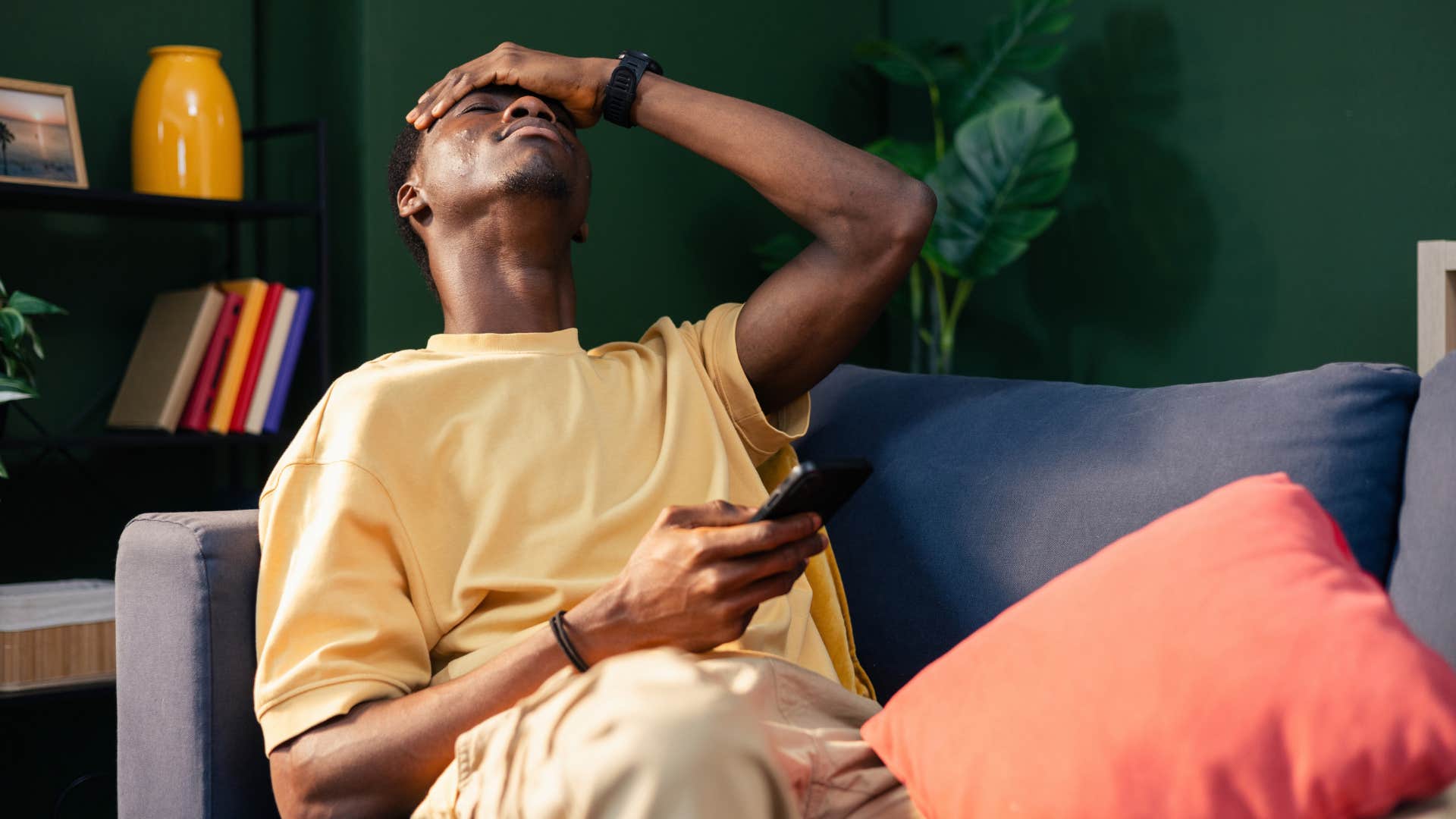 man holding his head who would rather do anything than call his parents still dealing with childhood trauma
