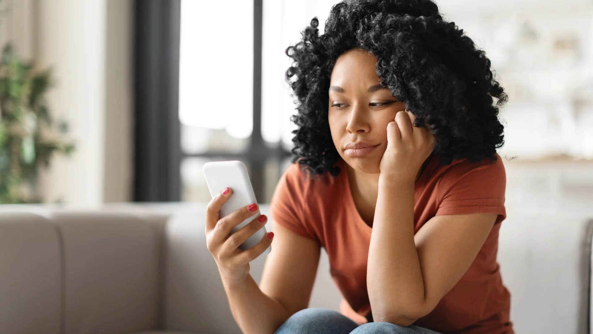 woman looking at phone would rather do anything than call her parents because she doesn't know what to say to them