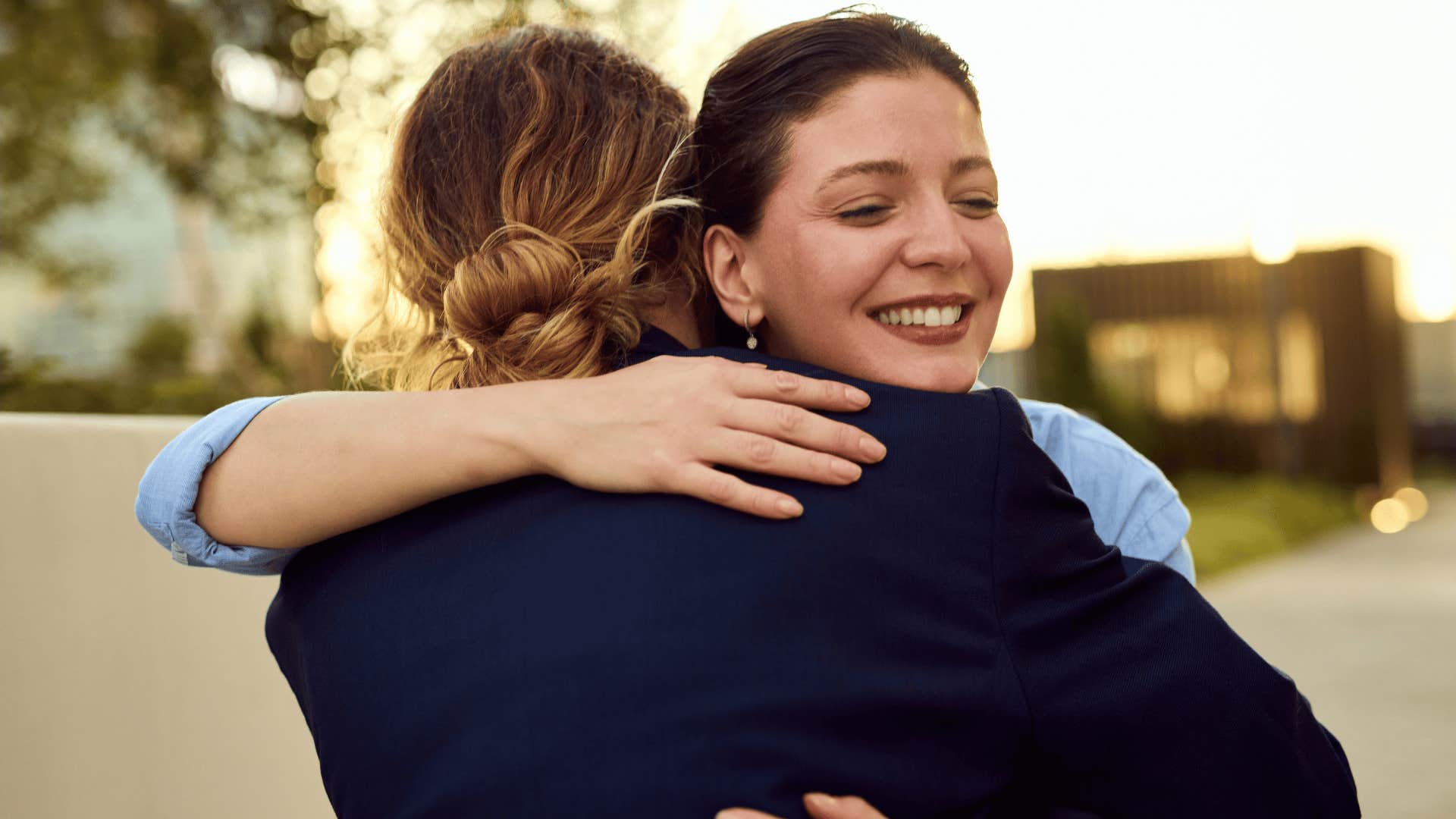 woman in blue shirt hugging friend as the universe places her around people who challenge her