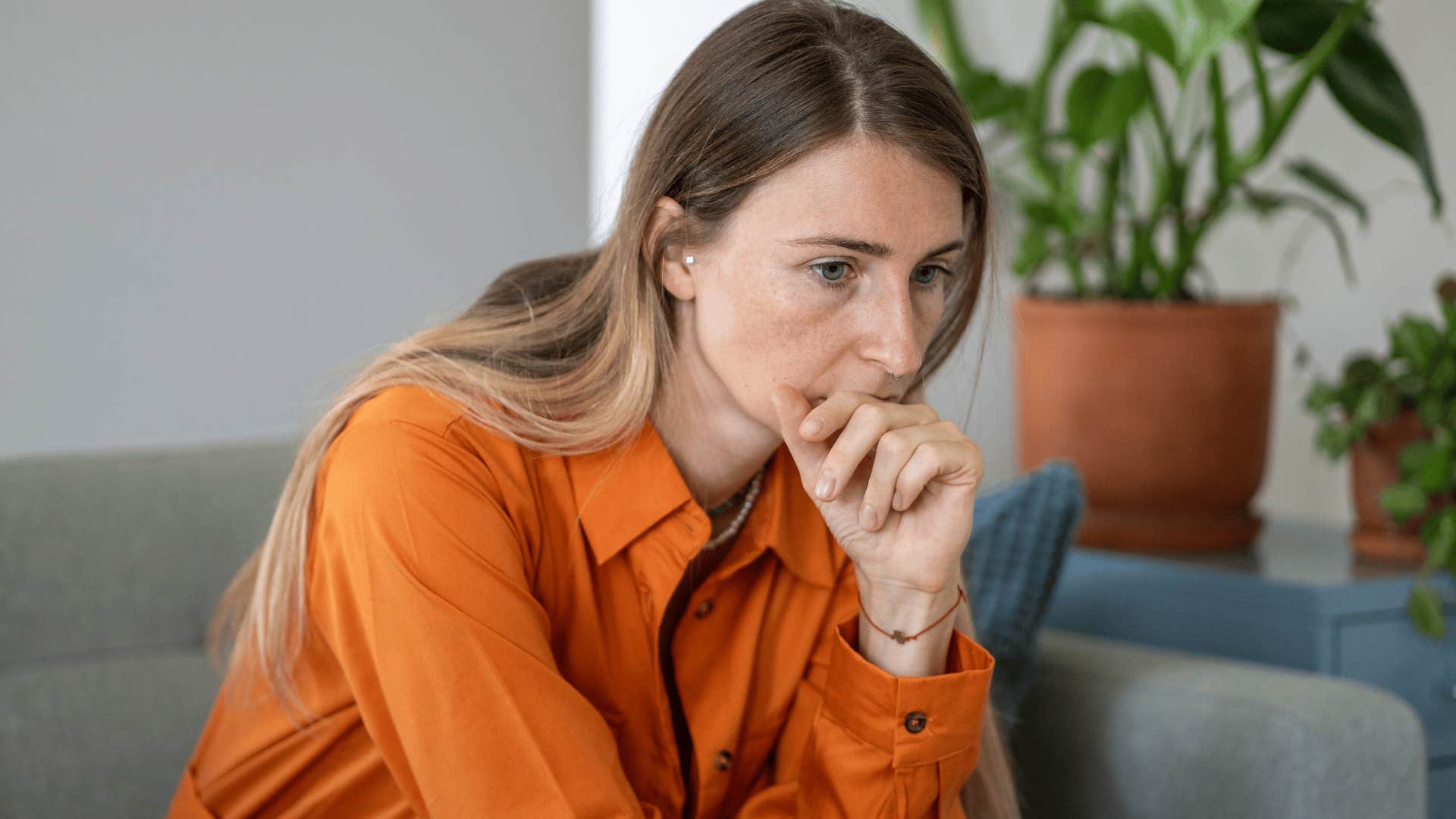 woman in orange shirt thinking deeply as the universe puts her in situations that require her to trust her intuition