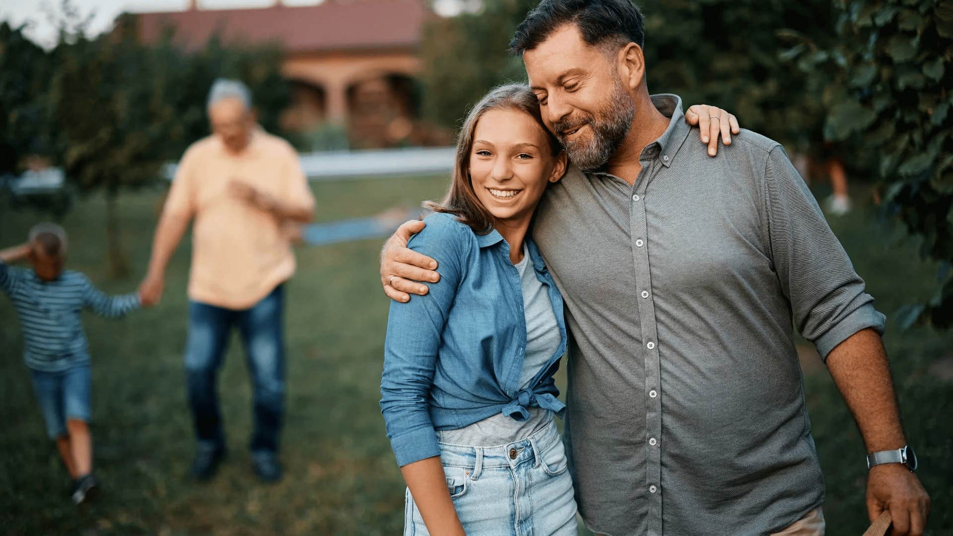 gen Z dad hugging his daughter in the backyard