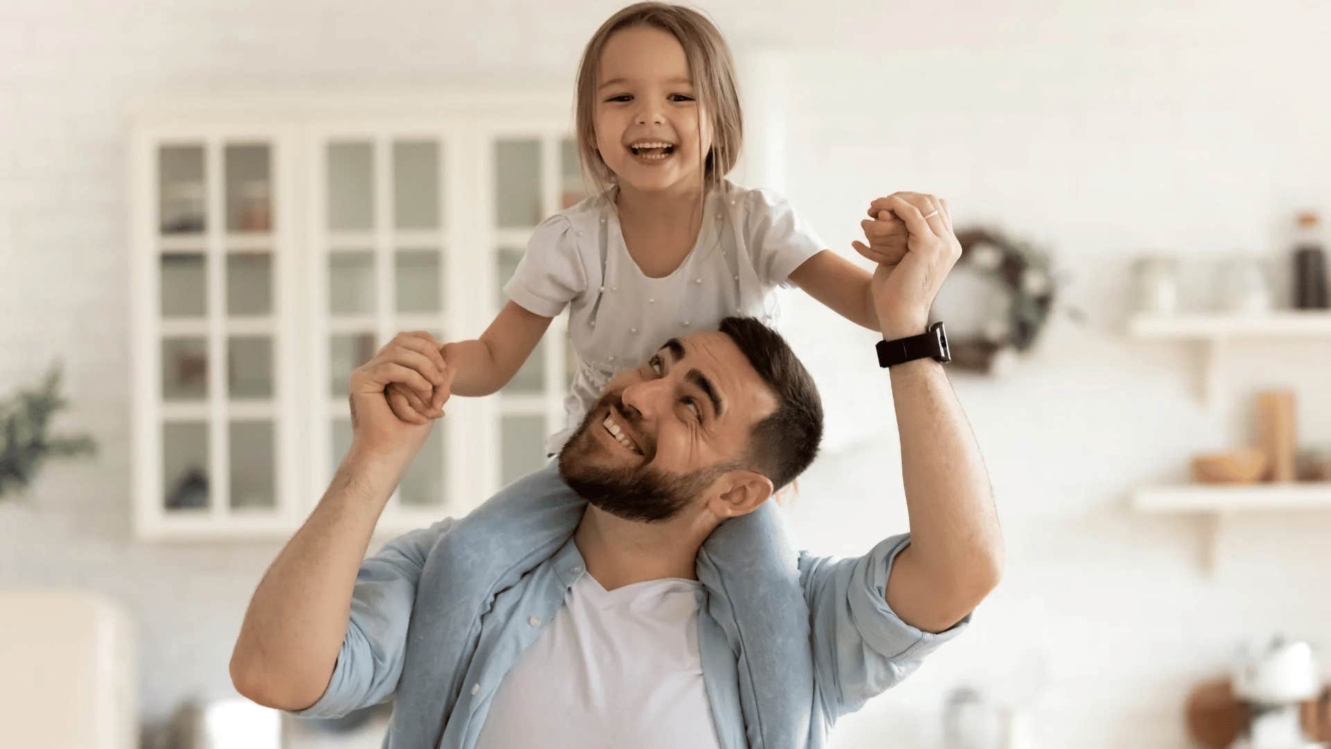 happy gen Z dad holding daughter on his shoulders