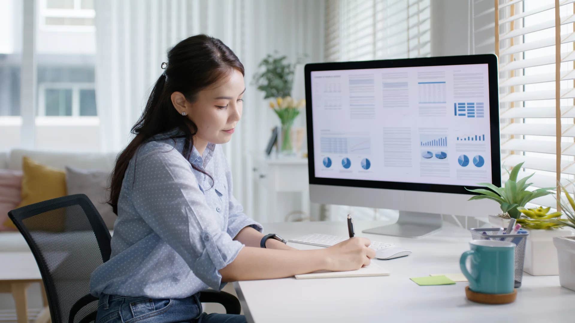young woman at work writing near a computer