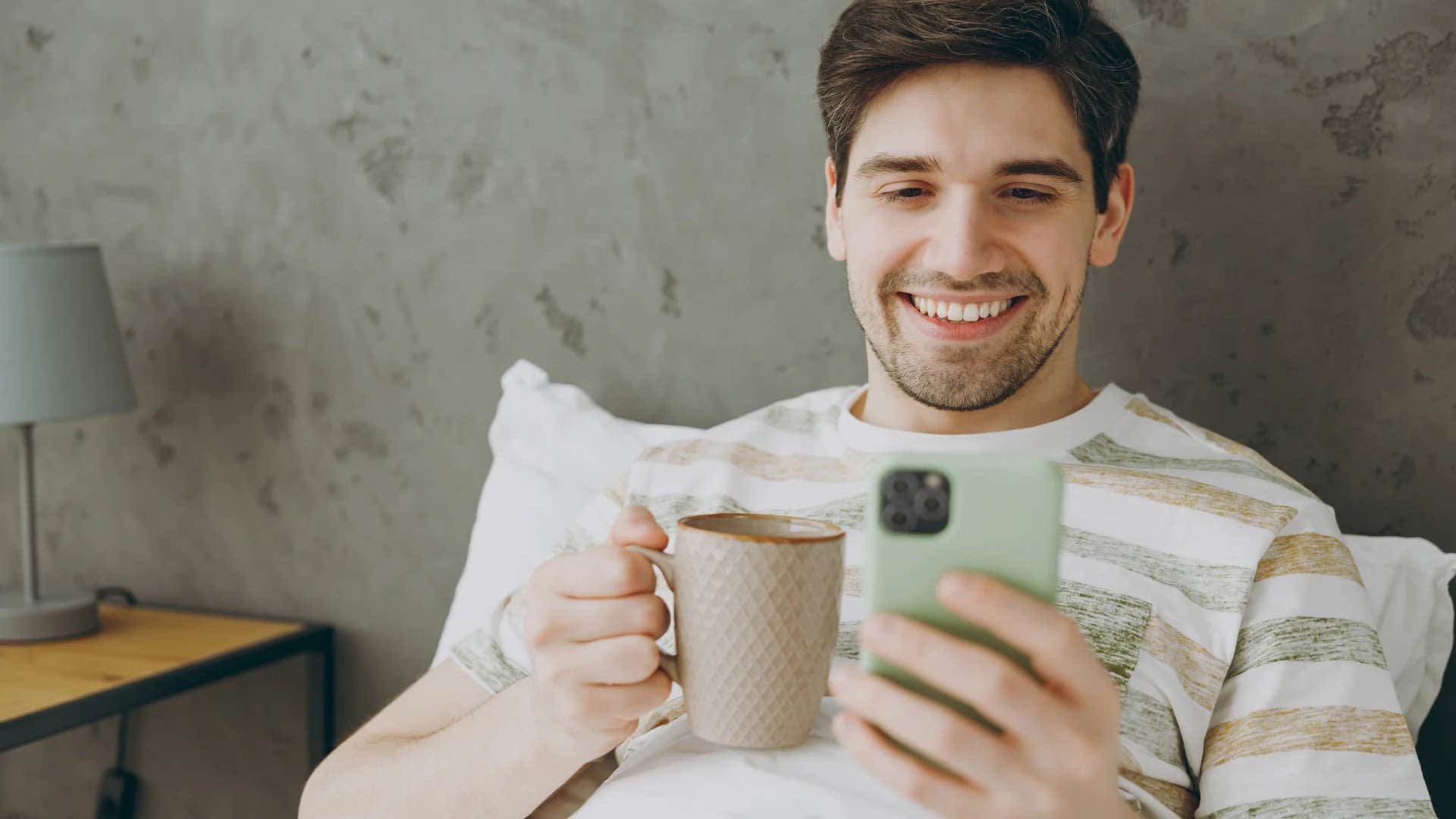 young man in bed on his phone 