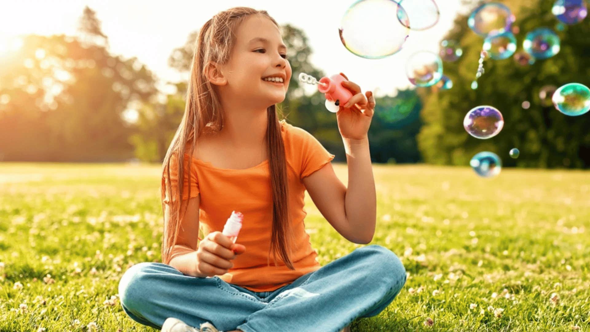 young girl blowing bubbles outside