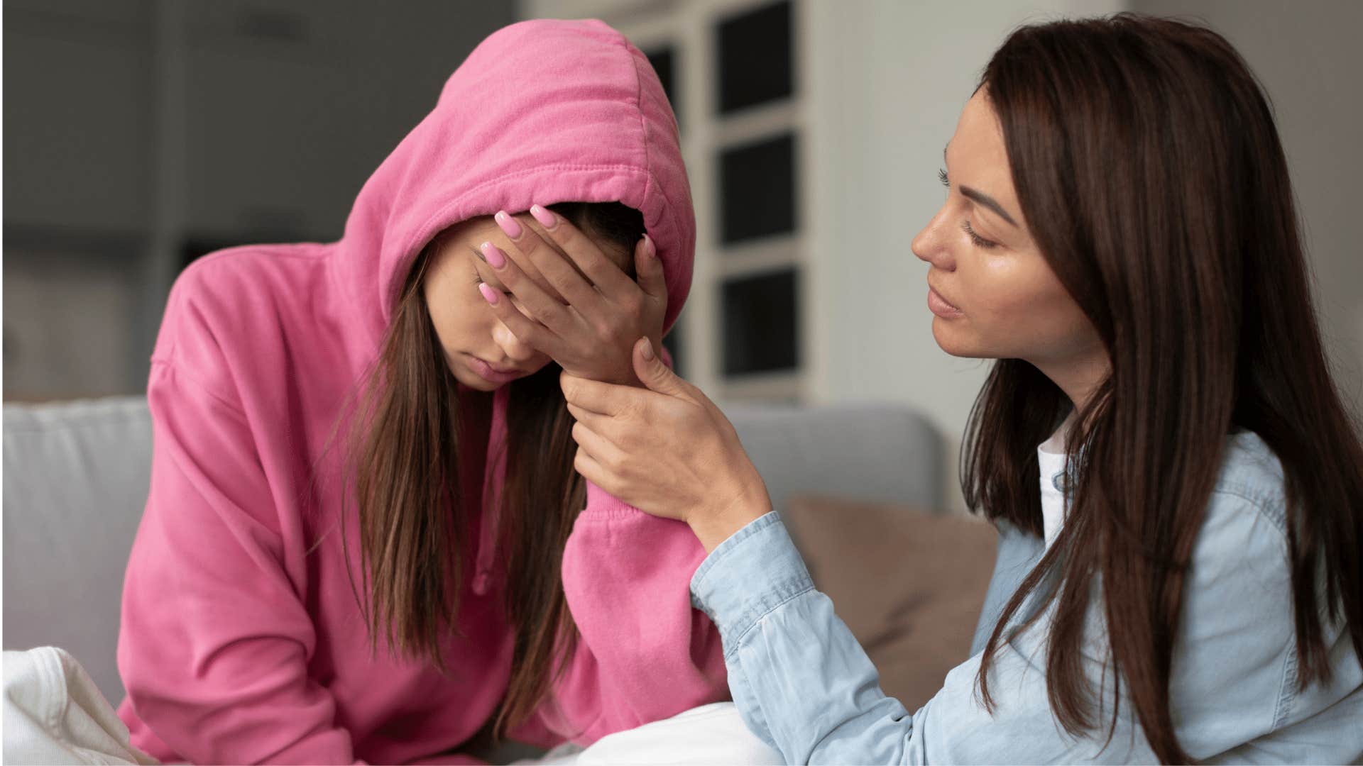 woman comforting daughter in pink hoodie as she wonders if the child has a problem