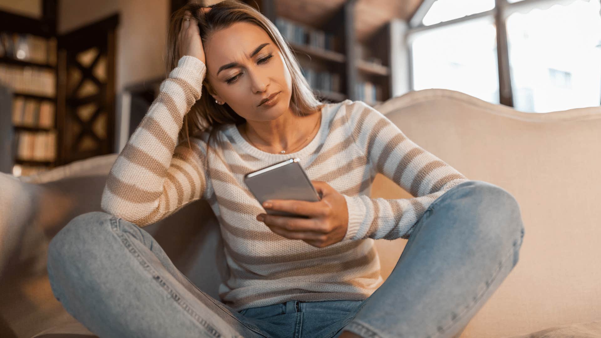 woman in white stripped shirt wondering who can i turn to for help as she looks at phone
