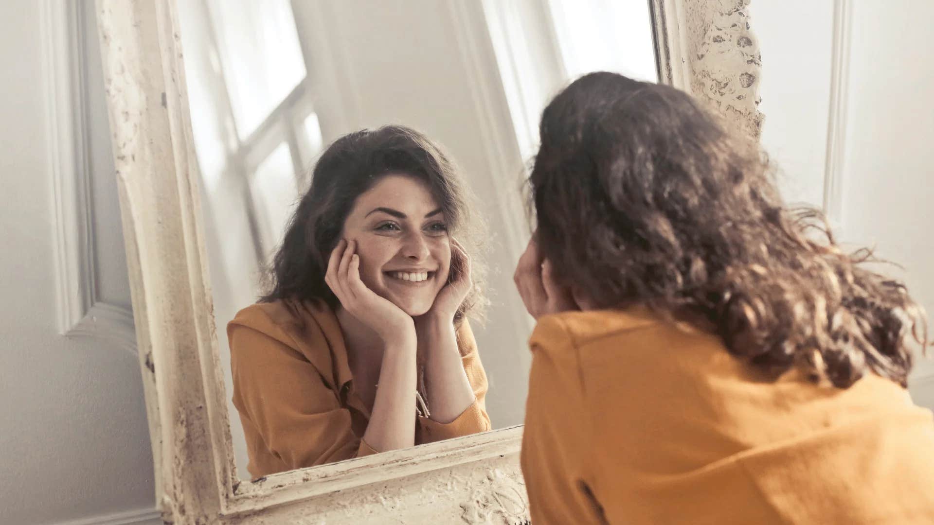 woman looking in mirror reminding herself i'm not in competition with anyone