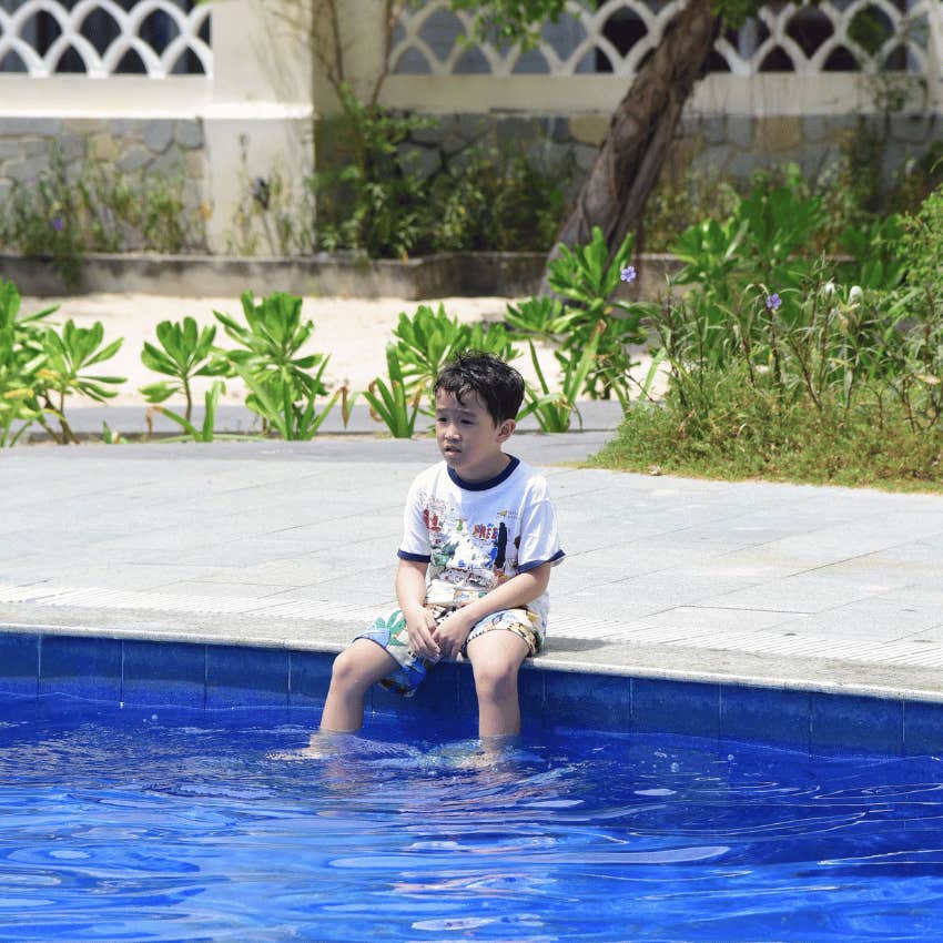 young boy sitting on the side of a pool
