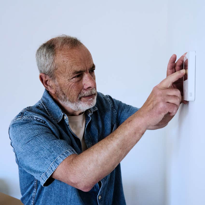 Boomer man shifting the thermostat before leaving the house.