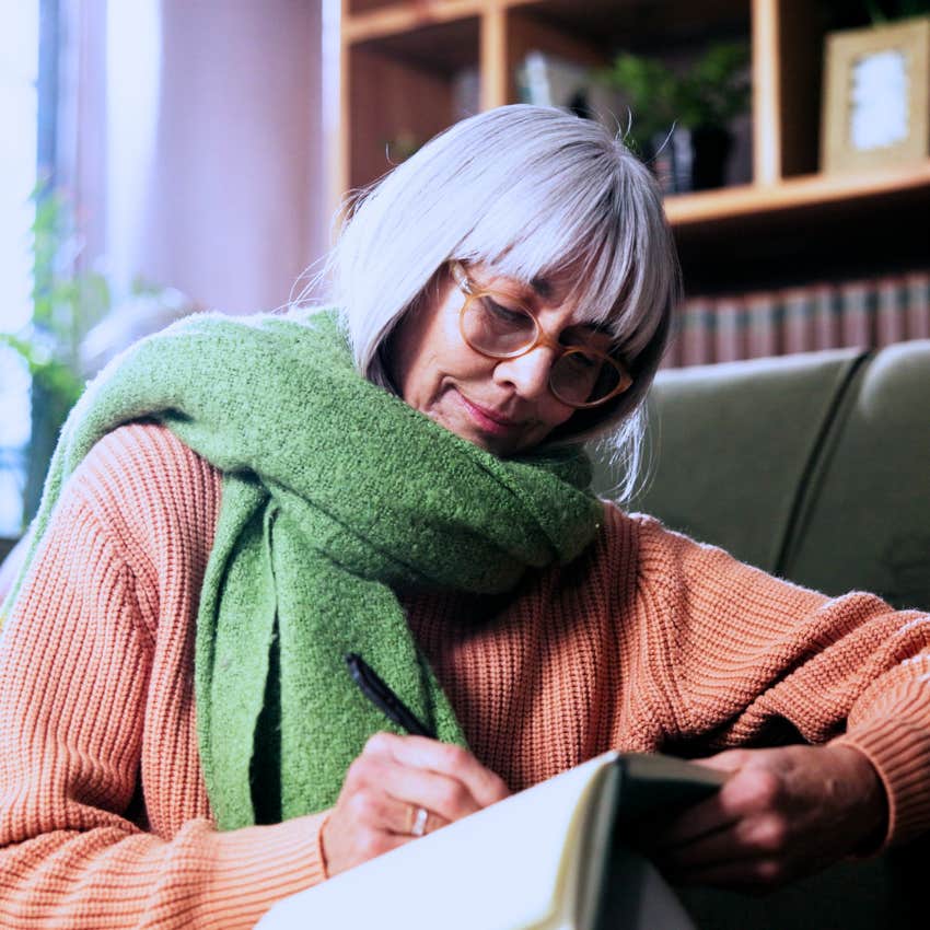 Boomer woman writing a to-do list on paper before leaving the house.