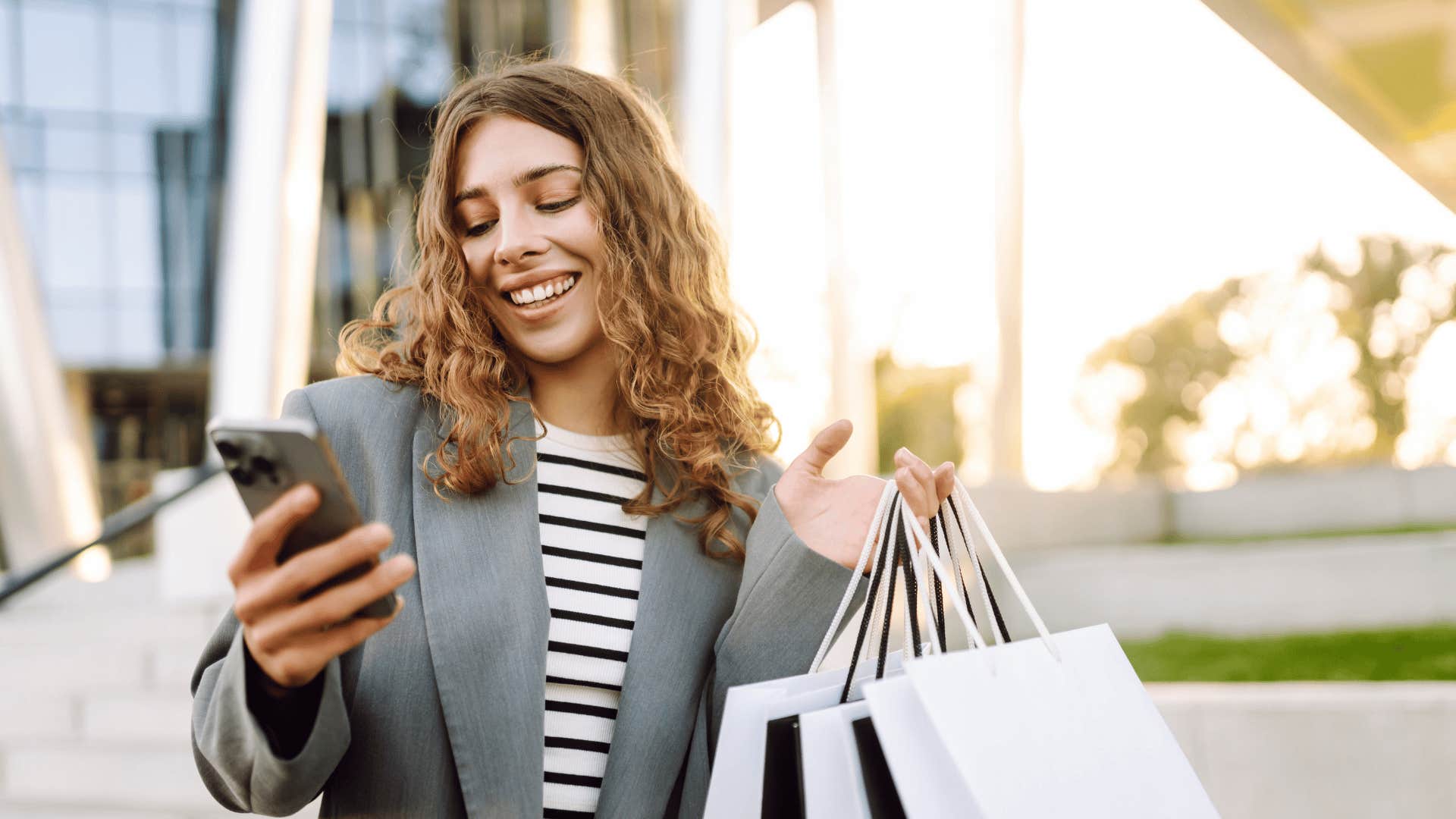 woman in stripped shirt smiling at phone as she doesn't wonder what counts as a worthwhile purchase