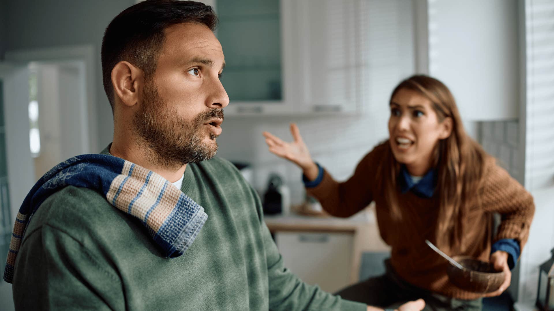 couple arguing about whether dishes need to be washed before bed as man in green shirt looks annoyed