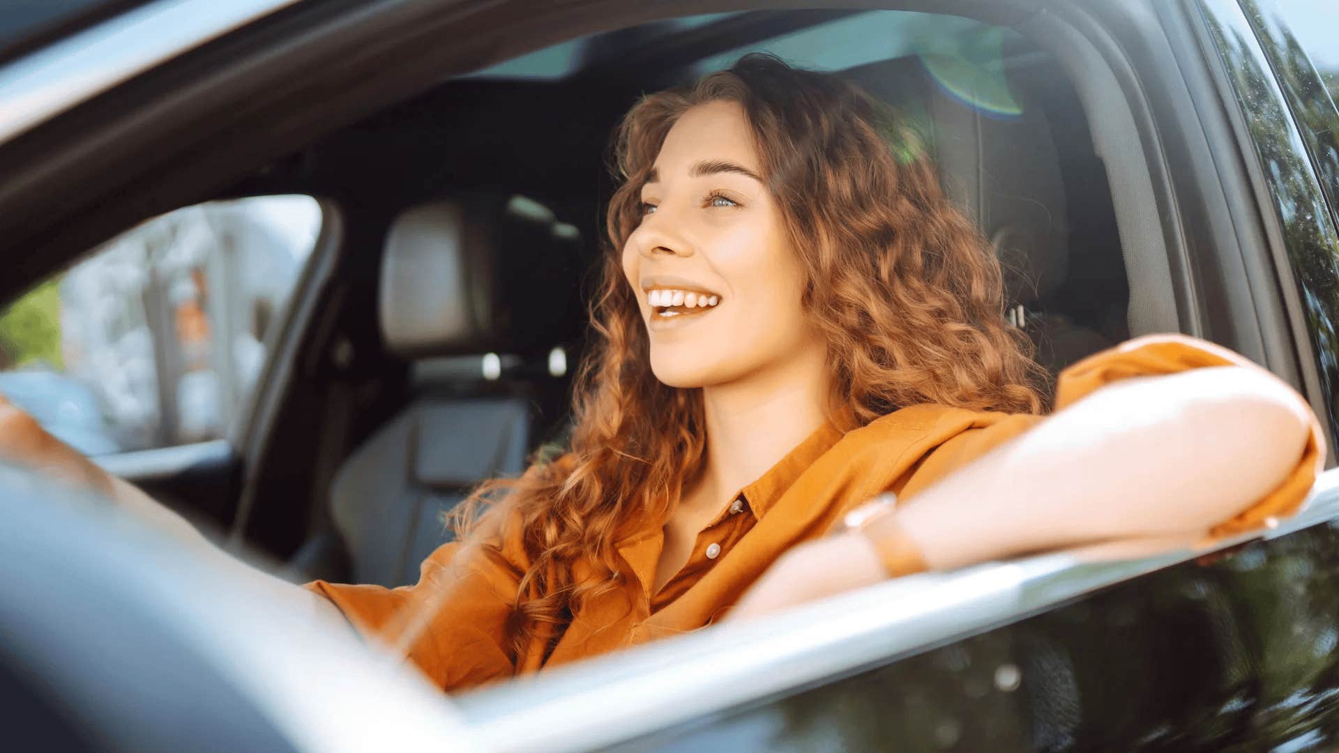 happy millennial woman driving older car