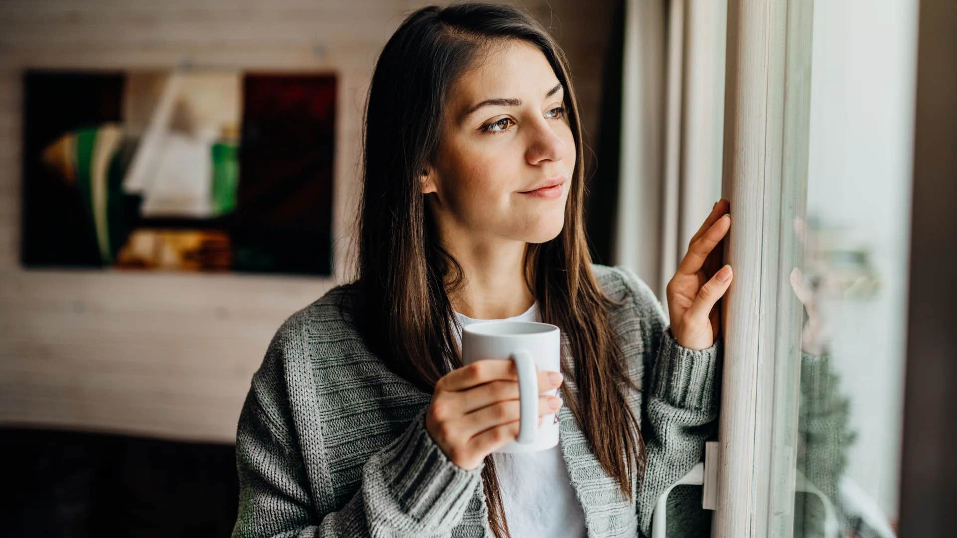 nostalgic millennial woman looking outside thinking