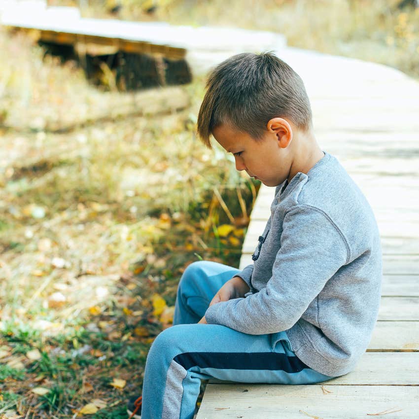 good kid who looks sad from a mistake sits on a pathway, head down