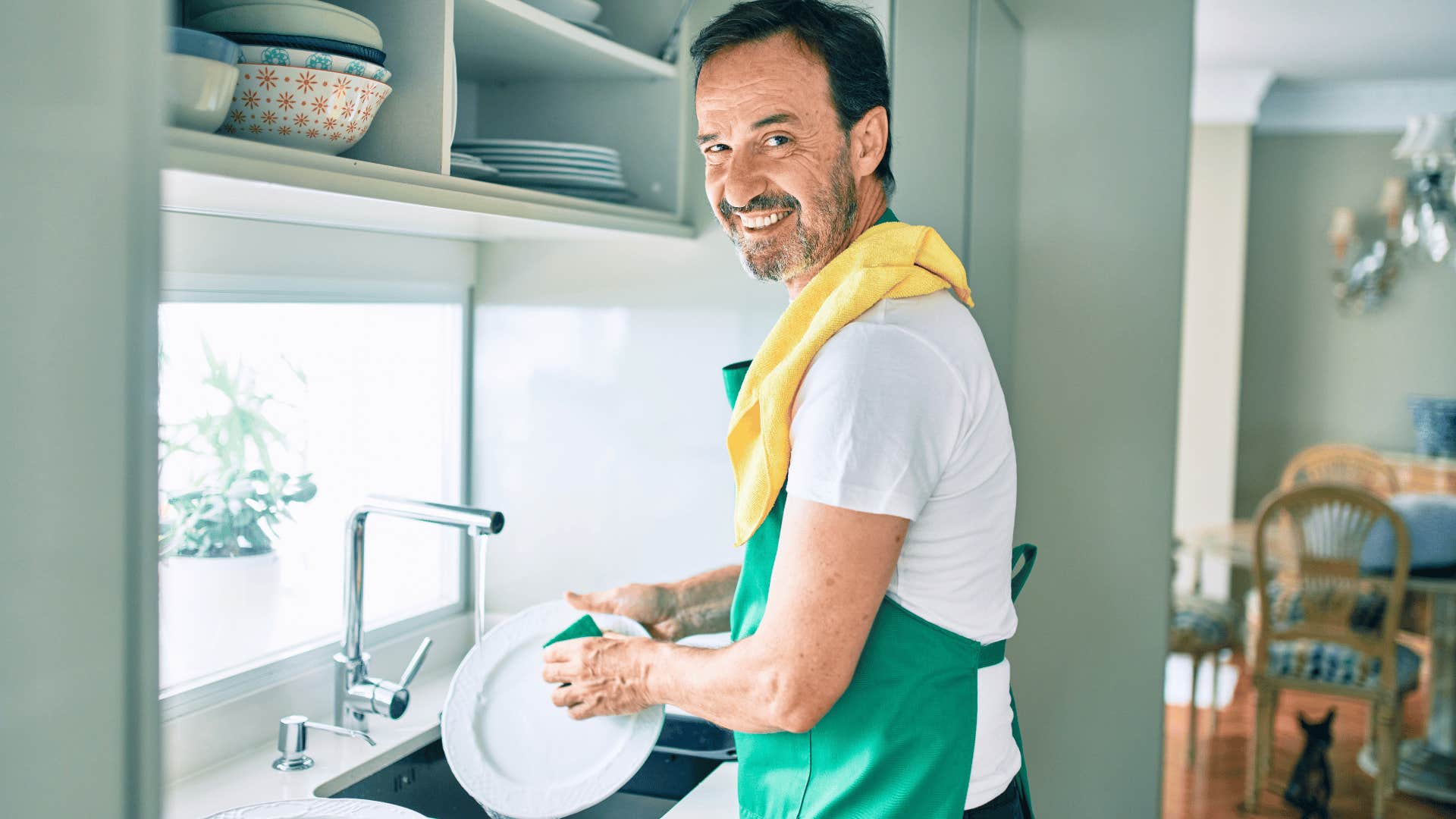 man in green apron hand washing dishes instead of using a dishwasher