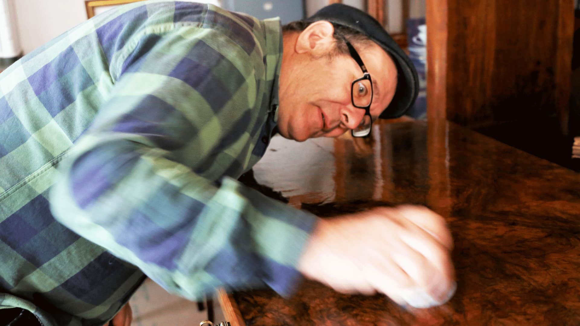 man in plaid shirt polishing wooden furniture with furniture wax