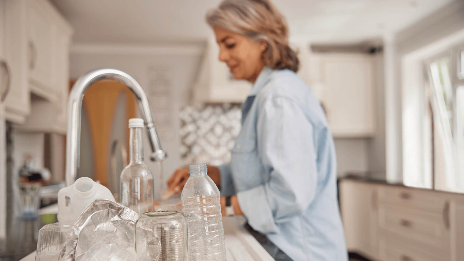 woman in blue shirt washing and reusing plastic containers
