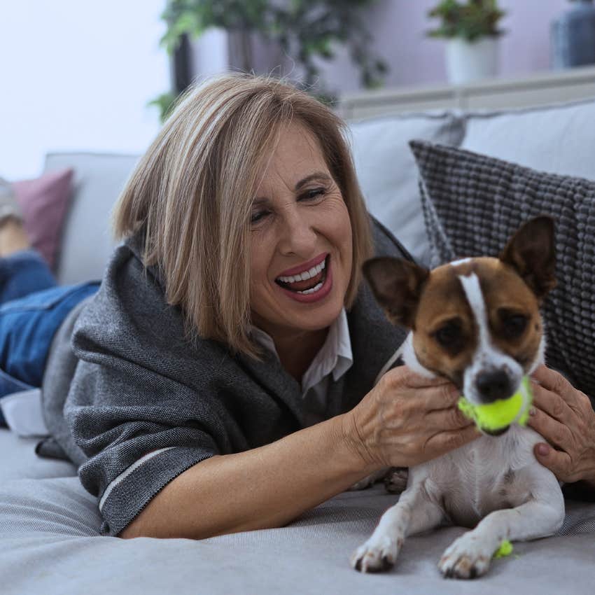Gen X woman spoiling her dog smiling as she pets him