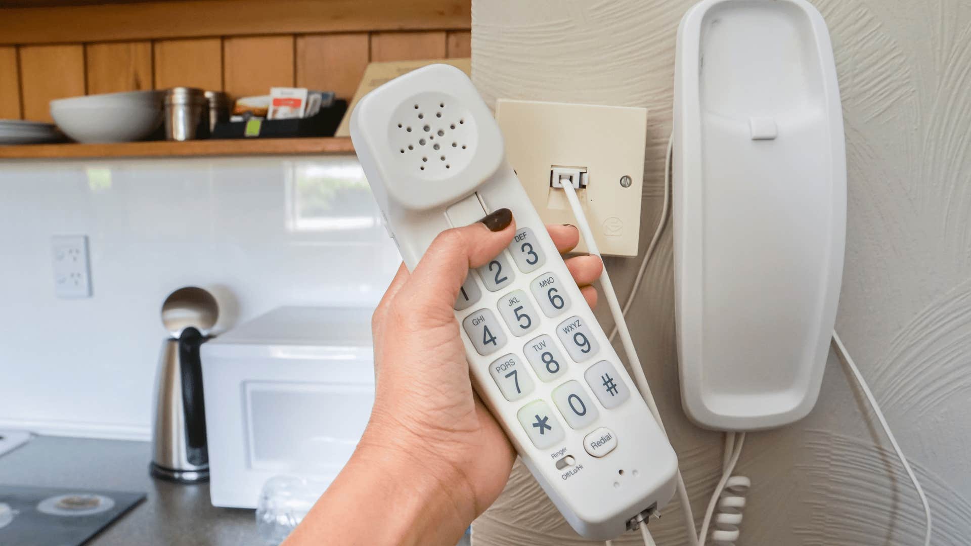 landline on the wall as woman dials number