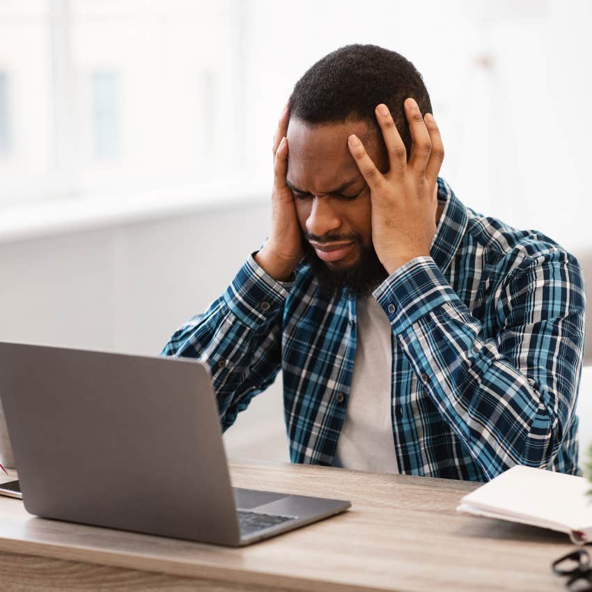 man sitting at computer with head in his hands feels dissatisfied with himself because he was raised by parents who made everything a competition