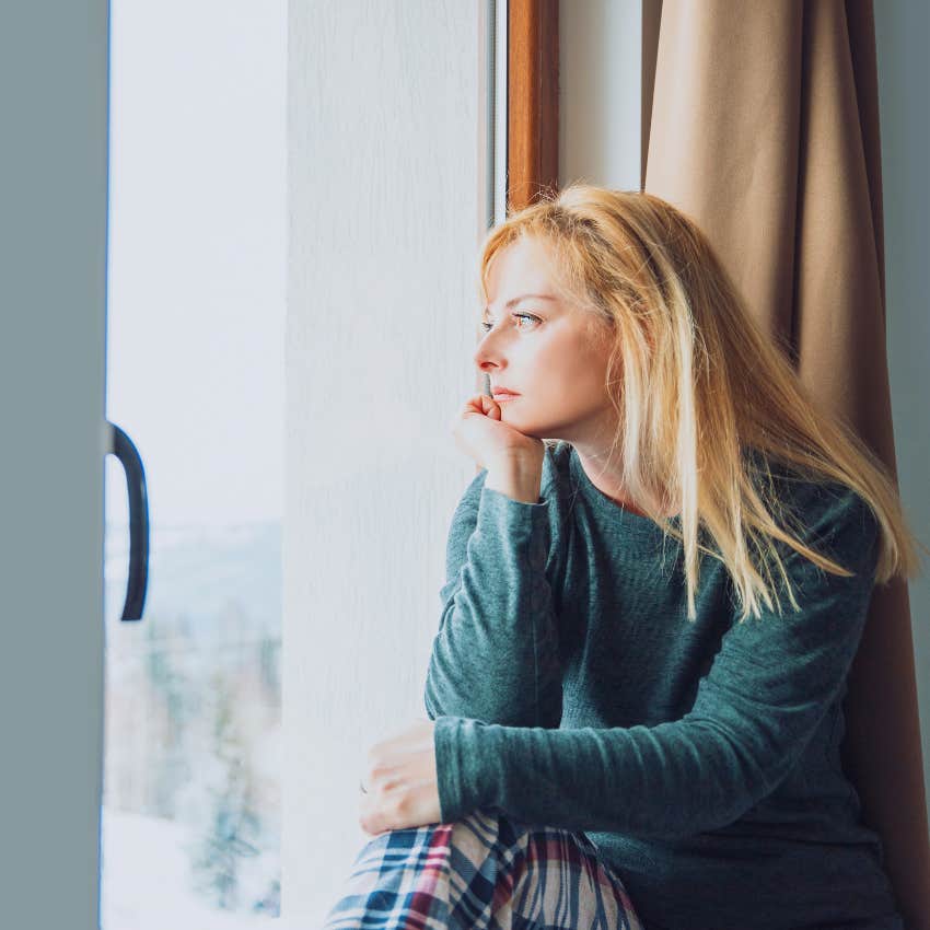 woman looking sadly out the window alone