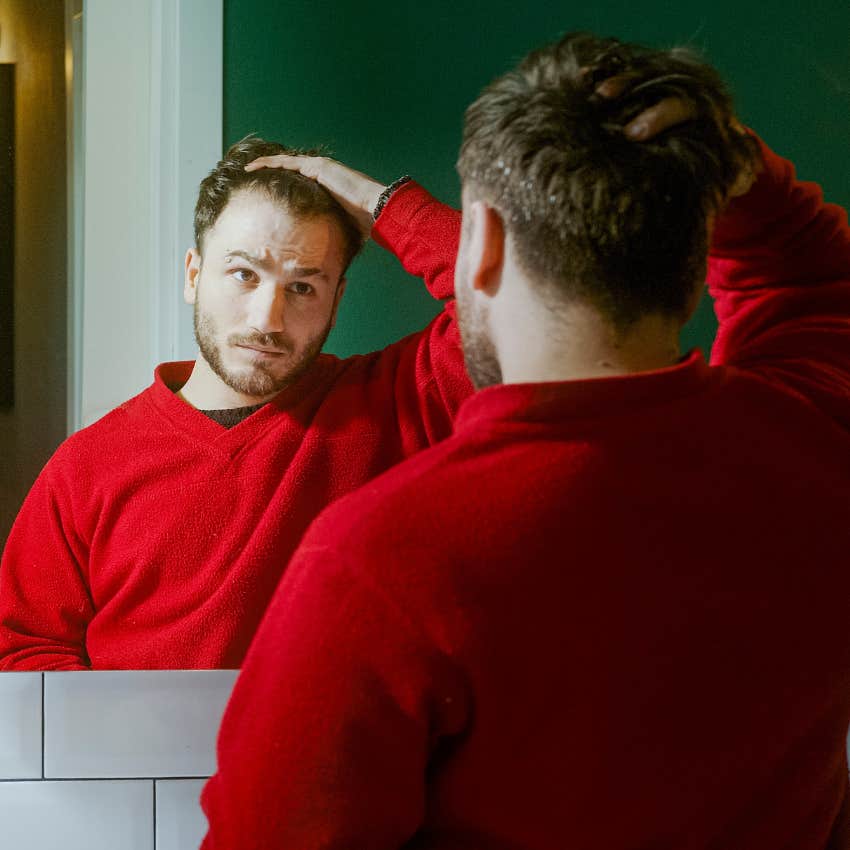 man suppressing emotions being critical of himself looking in the mirror