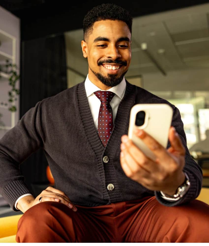 unique man smiling at himself in his phone 