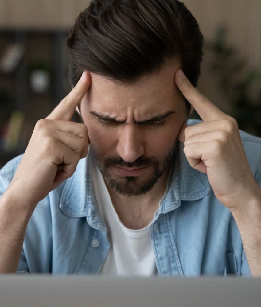man who looks like he's losing emotional control with fingers on his temples and eyes closed